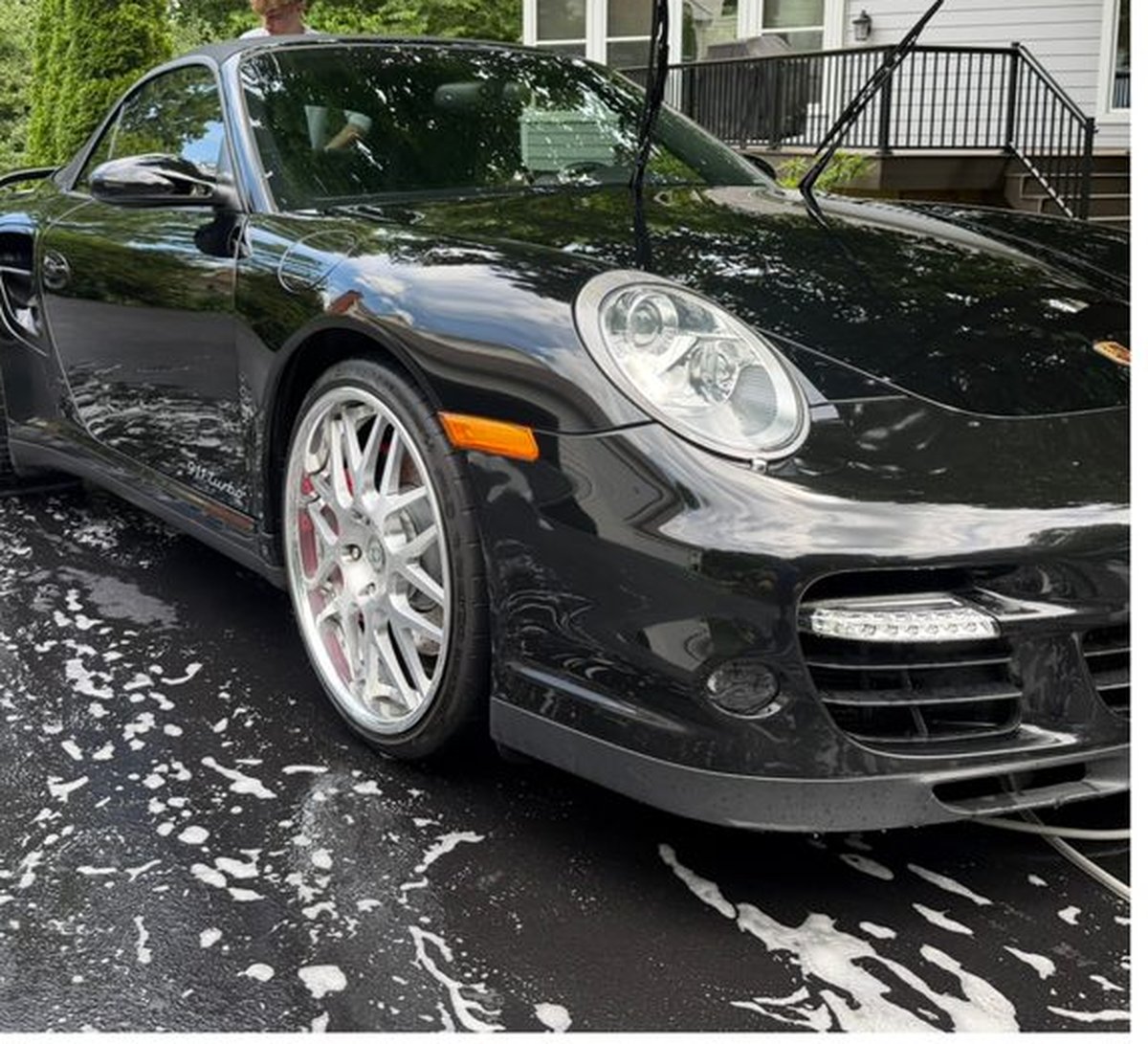Black Porsche mid-wash during an exterior detail